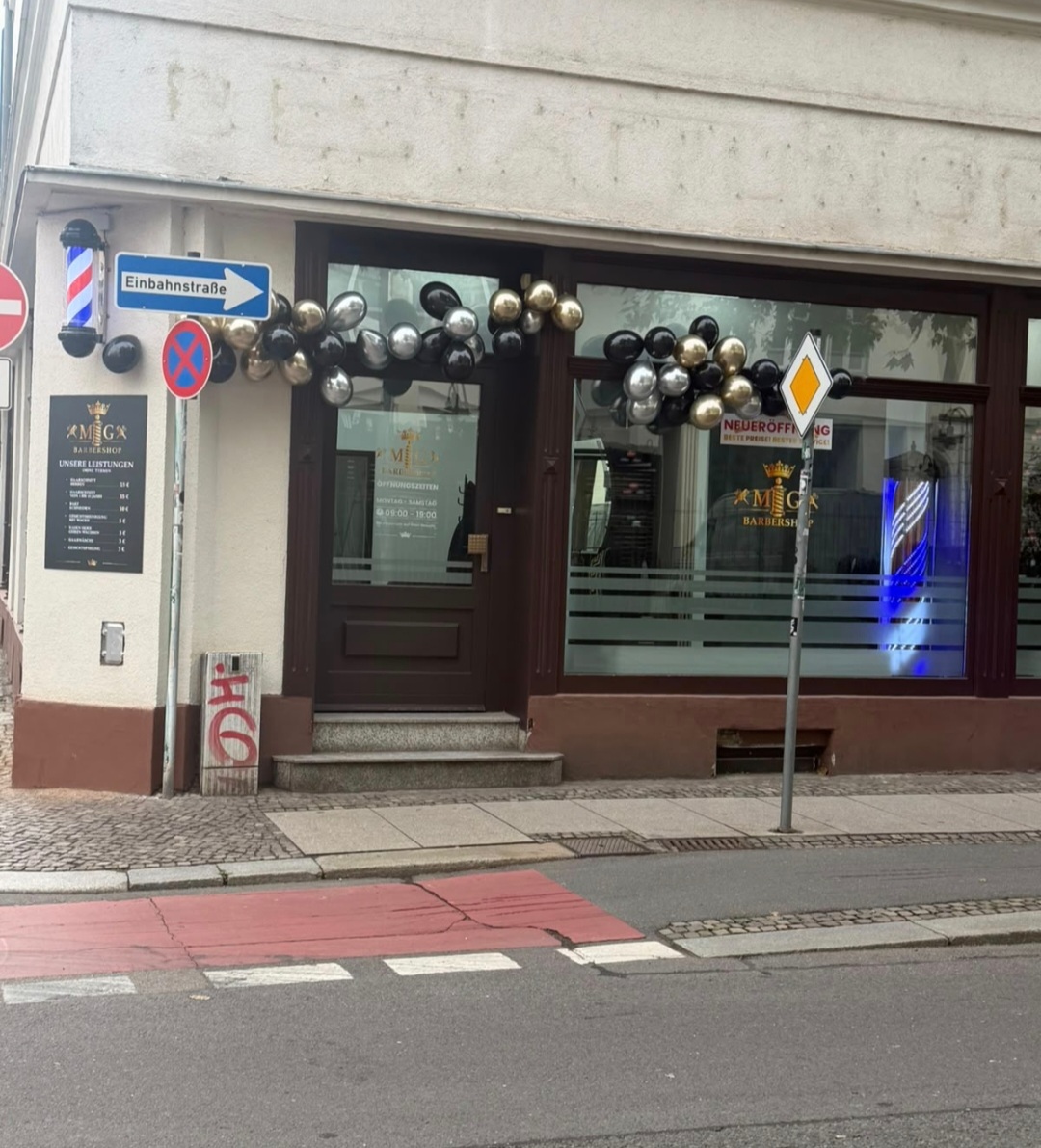 Eingang des MG Barbershops mit goldenen und schwarzen Ballons